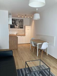 ein Wohnzimmer mit einem Tisch und Stühlen sowie eine Küche in der Unterkunft Marcelin Apartments Poznań in Posen
