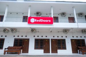 Un cartel de puerta rojo en el costado de un edificio en RedDoorz near Plaza Ambarrukmo Yogyakarta, en Seturan