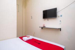 a room with a bed and a flat screen tv at RedDoorz near Plaza Ambarrukmo Yogyakarta in Seturan