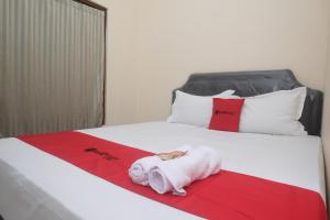 a white bed with a towel on a red blanket at RedDoorz near Plaza Ambarrukmo Yogyakarta in Seturan