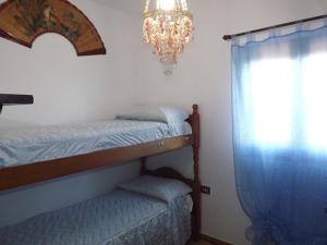 a bedroom with a bed and a chandelier and a window at Calasapone Holiday Home in SantʼAntìoco