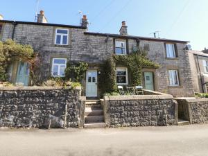 a stone house with a stone wall in front of it at Angel's Cottage in Buxton