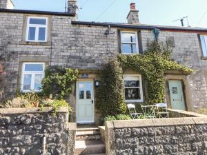 a stone house with a blue door and ivy at Angel's Cottage in Buxton