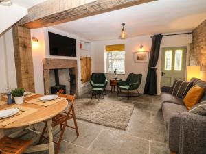 a living room with a couch and a table and a fireplace at Angel's Cottage in Buxton