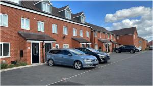 two cars parked in a parking lot in front of a brick building at Luxury Rooms in a 3-Bedroom House, Living Room, Kitchen, Big garden only 8mins away from Coventry City Centre in Coventry