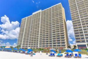 a large building with beach chairs and blue umbrellas at Beachfront Studio #909 at Majestic in Panama City Beach