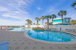 a swimming pool with palm trees and a house at Beachfront Studio #909 at Majestic in Panama City Beach