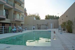a swimming pool with people sitting on benches next to a building at Lovely & Lightful Studio with pool in San Fernando