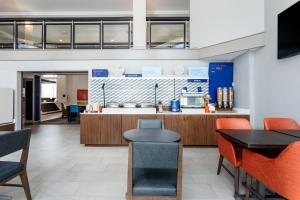 a restaurant with a counter and tables and chairs at Holiday Inn Express Hotel Clearwater East - ICOT Center, an IHG Hotel in Pinellas Park