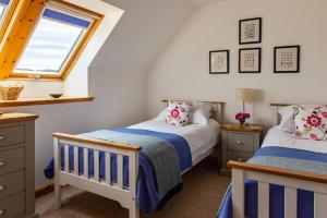 two beds in a attic bedroom with a window at Shore Croft in Aultbea