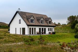 una casa blanca con techo de gambrel en una colina en Shore Croft, en Aultbea