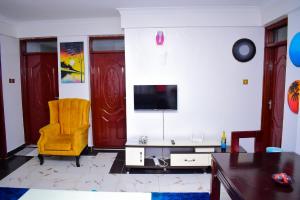 un soggiorno con sedia gialla e TV di Bomani Penthouse a Kisumu