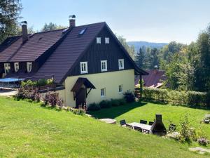 ein großes weißes Haus mit schwarzem Dach in der Unterkunft Chalupa Na Pustinách in Jablonec nad Nisou