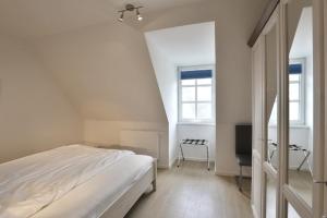 ein weißes Schlafzimmer mit einem Bett und einem TV in der Unterkunft Residenz am Balmer See - BS 69 mit Wellnessbereich in Balm