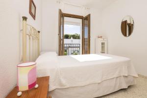 a white bedroom with a large bed and a window at Casa Ocon in Conil de la Frontera