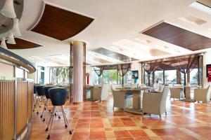 a restaurant with a bar with chairs and tables at Le Meridien Al Aqah Beach Resort in Al Aqah