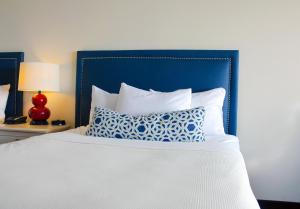a bed with a blue headboard and a pillow on it at Dunes Suites Oceanfront in Ocean City