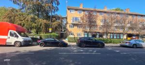 3 auto parcheggiate in un parcheggio accanto a un edificio di St Albans Village Studios by DC London Rooms a Londra
