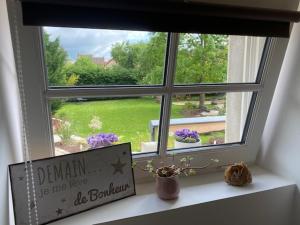 a window with a window sill with a sign and flowers at Bienvenue au Gite La So Sweet in Rully