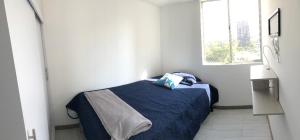 ein Schlafzimmer mit einem blauen Bett in einem weißen Zimmer in der Unterkunft Apartamento confortable y excelente ubicación in Bello