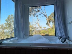 a bath tub with a large window in a bathroom at Pousada Recanto das Cachoeiras in Urubici