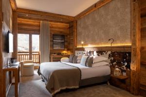 a bedroom with a bed and a desk and a window at M Lodge & Spa in Saint-Martin-de-Belleville