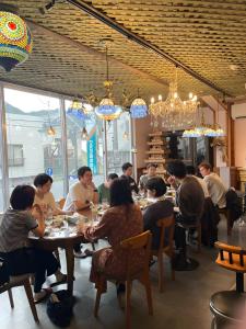 a group of people sitting at a table in a restaurant at まちやど　Motomachi in Daigo