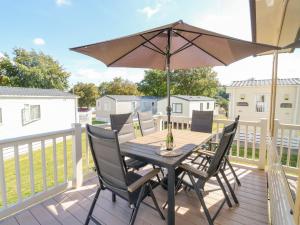 a wooden table with an umbrella on a deck at E10 Eagle Meadows in Paignton