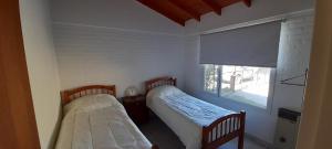 2 łóżka w małym pokoju z oknem w obiekcie Los Choiques Madryn w mieście Puerto Madryn