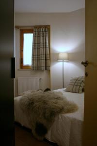 ein Schlafzimmer mit einem weißen Bett mit einem pelzigen Teppich darauf in der Unterkunft Appartamento Arnolucci in Rovere