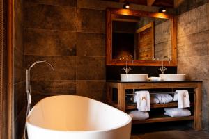 a bathroom with a tub and two sinks and a mirror at M Lodge & Spa in Saint-Martin-de-Belleville +20 photos