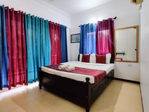 a bedroom with a bed with colorful curtains at Ivy Retreat- Serviced Apartments in Baga