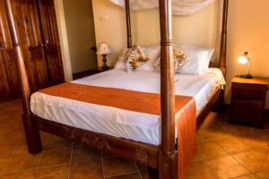 a bedroom with a four poster bed with white sheets at Sand and Shells Beach House- 4 Bedroom with a pool in Mombasa