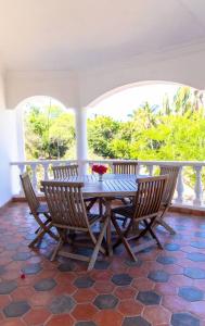 a wooden table and chairs on a porch with a table at Sand and Shells Beach House- 4 Bedroom with a pool in Mombasa