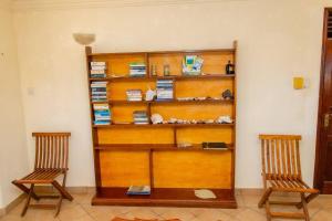 two chairs sitting next to a wooden book shelf at Sand and Shells Beach House- 4 Bedroom with a pool in Mombasa
