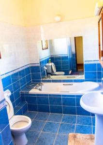 a blue tiled bathroom with a toilet and a sink at Sand and Shells Beach House- 4 Bedroom with a pool in Mombasa