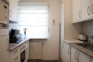 德勒斯登的住宿－Ferienwohnung Henniger，厨房配有白色橱柜和窗户。