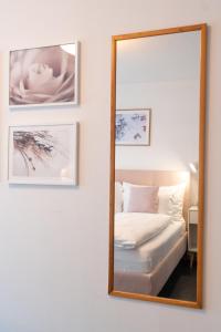 einen Spiegel an der Wand mit einem Bett und gerahmten Bildern in der Unterkunft la belle vue Boutique Hotel & Café in Spiez