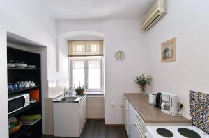 a white kitchen with a sink and a window at Apartment Stross Rijeka in Rijeka +5 photos