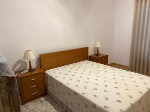a bedroom with a bed and two night stands with lamps at Quinta da Travessa in Cinfães