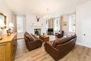 a living room with leather furniture and a fireplace at Coach House, Middleton Hall Estate in Belford