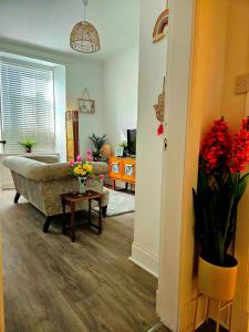 a living room with a couch and a table with flowers at The Ferns - Shared Garden Apartment With Parking in Darvel