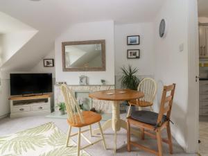 a living room with a table and chairs and a tv at 2 Station Road East in Peterculter