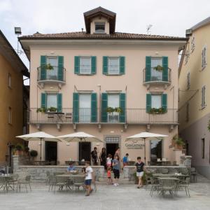um edifício com mesas e guarda-chuvas à sua frente em Casa Castagna 1620 em Mergozzo