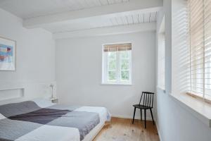 a white bedroom with a bed and a chair at Hygge Hus in Oevenum