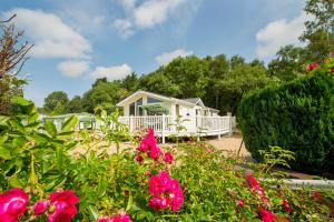 une maison blanche avec des fleurs roses devant elle dans l'établissement Beamish Holiday Park, à Stanley
