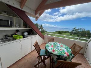 a kitchen with a table and chairs on a balcony at Studio Cannelle Vue Mer Village Vacances Sainte Anne in Sainte-Anne