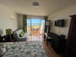 - une chambre avec un lit, un bureau et une télévision dans l'établissement Studio Cannelle Vue Mer Village Vacances Sainte Anne, à Sainte-Anne