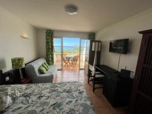 a bedroom with a bed and a desk and a television at Studio Cannelle Vue Mer Village Vacances Sainte Anne in Sainte-Anne