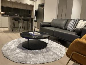 ein Wohnzimmer mit einem schwarzen Sofa und einem Tisch in der Unterkunft Superior 3 Bedroom 2 Bathroom Apt Melbourne CBD in Melbourne